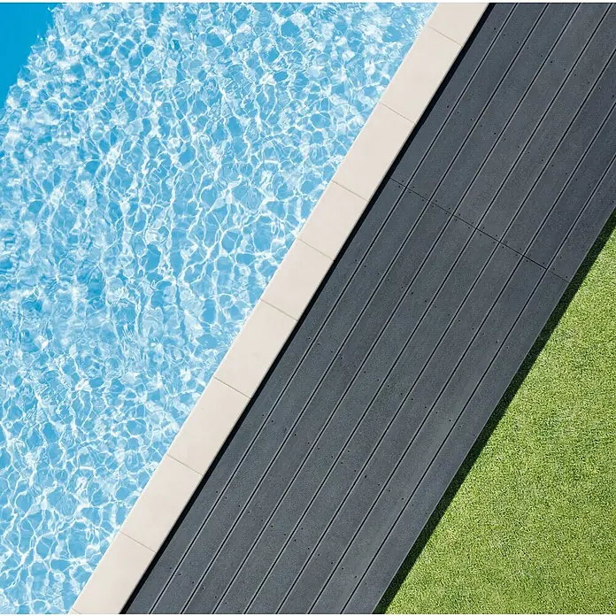 Desjoyaux Bausatz-Pool Jou - L x B x H: 600 x 300 x 120 cm, 20.000 l, Weiß - Blick von oben auf einen Pool mit stilvollem, dunkelgrauem Terrassenboden und gepflegtem Rasen. Das perfekte Ambiente für entspannte Stunden im Freien.