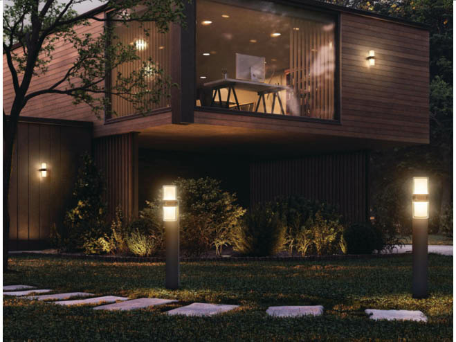 Gewächshaus bei Nacht im Garten mit schwarzem Rahmen und Glas, wie ein Wohnzimmer gemütlich eingerichtet und mit Leuchten bestückt