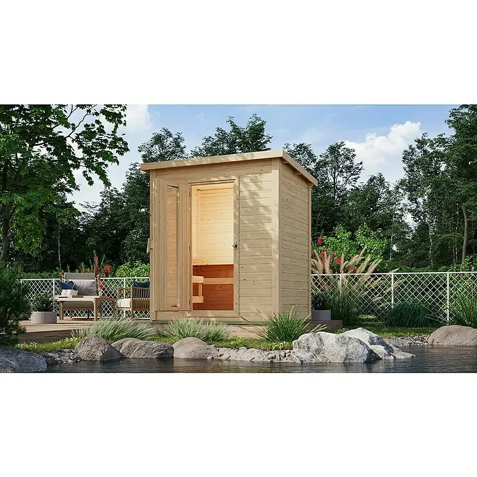Karibu Saunahaus Hytti - Ohne Ofen, L x B x H: 146 x 196 x 228 cm, Natur - Holzsauna im Freien mit geöffneter Tür. Die Sauna befindet sich neben einem kleinen Teich und einer Terrasse mit Gartenmöbeln.
