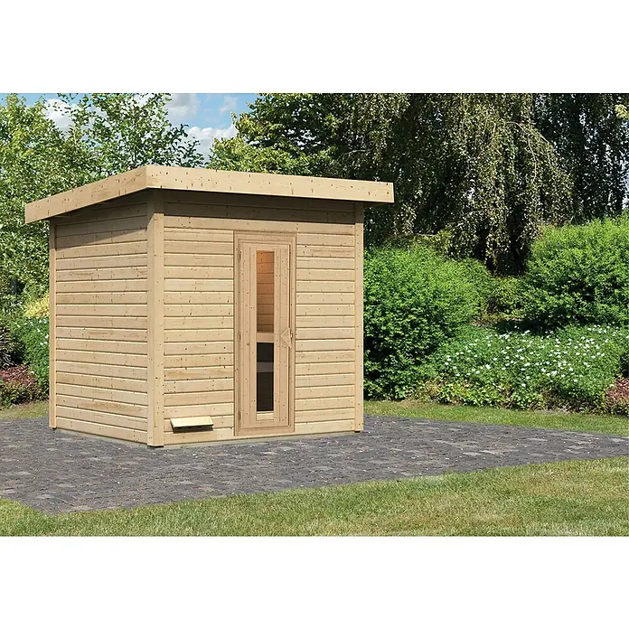 Karibu Saunahaus Hytti - Ohne Ofen, L x B x H: 196 x 231 x 228 cm, Natur - Eine helle Holzsauna mit Glastür auf einem gepflasterten Bereich in einem Garten, umgeben von Grün.