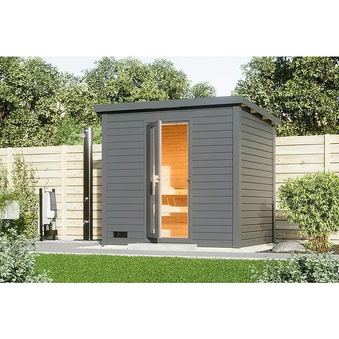 Karibu Saunahaus Hytti - Ohne Ofen, Terragrau, L x B x H: 196 x 231 x 228 cm - Das Bild zeigt eine moderne Gartensauna mit geöffneter Tür, die einen Blick ins Innere freigibt, umgeben von Grün.