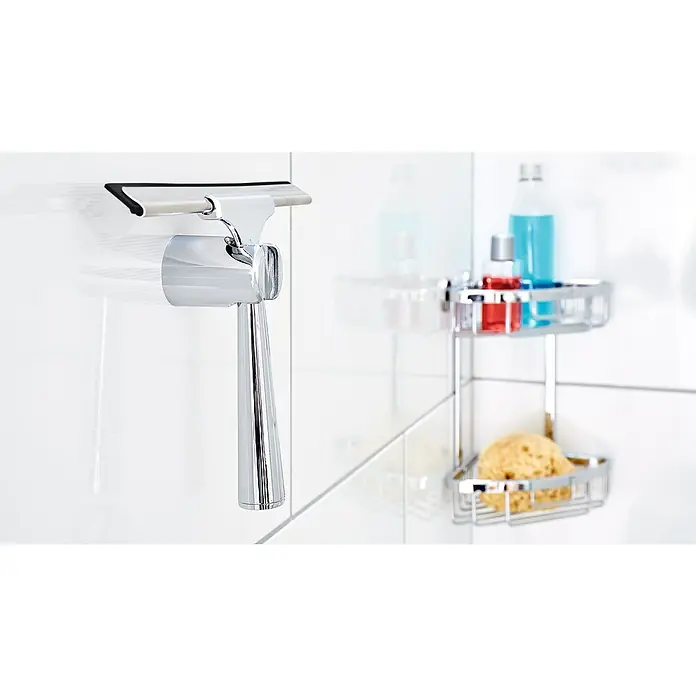 Tesa Bad- & Duschabzieher Spaa - Chrom - Ein chromglänzender Duschabzieher mit Halterung und ein Eckregal mit Badutensilien an einer weißen Wand.