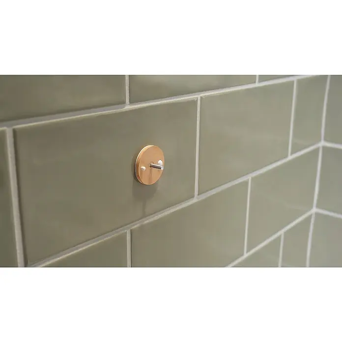 Tesa Aluxx Cesta de baño angular - L x An x Al: 16,3 x 16,3 x 26,2 cm, Negro, Recubrimiento en polvo - Primer plano de un toallero redondo de madera con un tornillo en una pared de azulejos verdes. Accesorio de baño práctico y elegante.