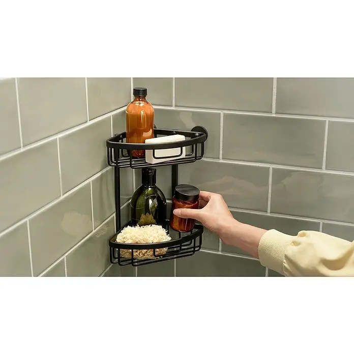 Tesa Aluxx Cesta de baño angular - L x An x Al: 16,3 x 16,3 x 26,2 cm, Negro, Recubrimiento en polvo - Estante de esquina de metal con dos niveles fijado a una pared de azulejos, que muestra productos de baño como jabón, botellas y esponja de baño.