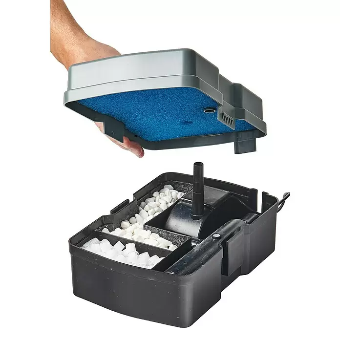 Heissner Unterwasserfilter - 5 W - Eine Person hält den grauen Deckel mit blauem Schwamm über einem schwarzen Aquarienfilter, gefüllt mit weißem Filtermaterial und einer Pumpe.