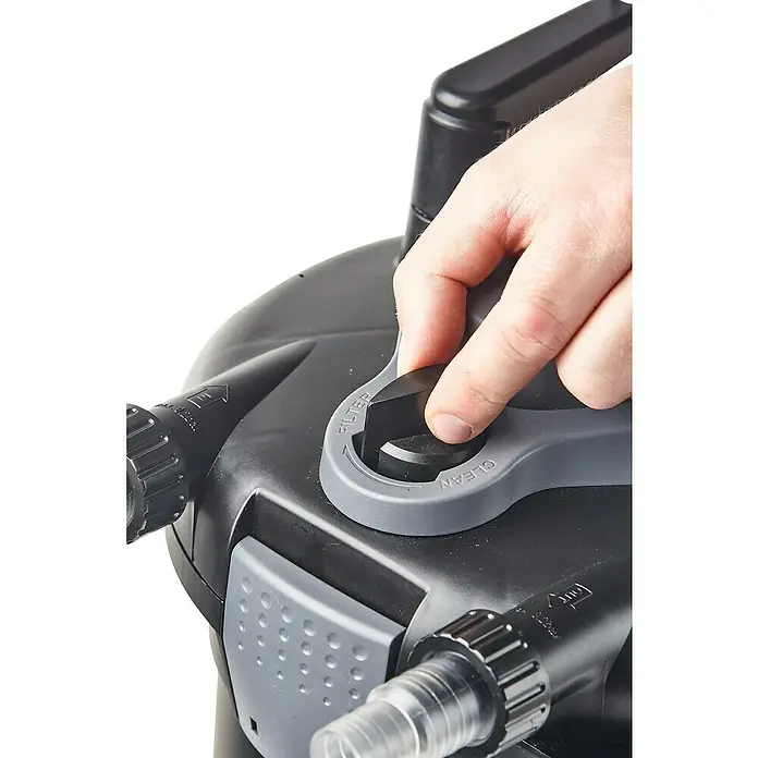 Heissner Druckfilter-Set - 25 W, Fördermenge pro Std.: 1.500 l - Nahaufnahme eines Teichfilters, wobei eine Hand den Reinigungsmechanismus betätigt, um eine saubere Wasserumgebung zu gewährleisten.