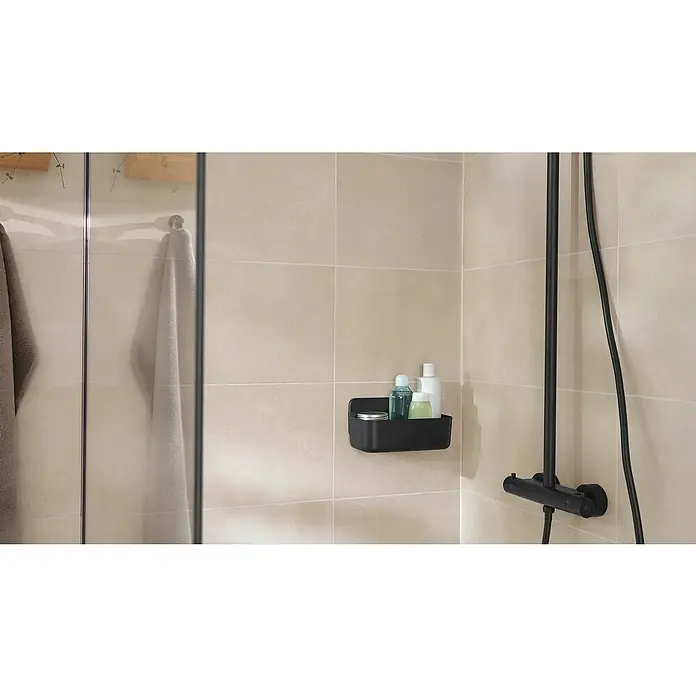 Tesa Duschkorb Lavaa - 26 x 11 x 13 cm, Schwarz, Matt - Ein schwarzer Duschkorb mit Shampoo, Duschgel und einer Dose an einer beigen, gefliesten Duschwand.