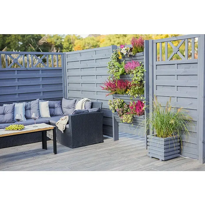 Pflanzkasten Torino - Außenmaß (L x B x H): 34 x 34 x 34 cm, Holz, Grau - Ein grauer Gartenzaun mit integrierten Pflanzkästen, die mit bunten Blumen und Grün bepflanzt sind, neben einem gemütlichen Sitzbereich.