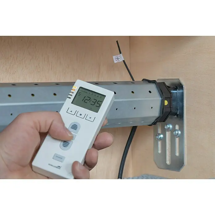 Schellenberg Funk-Rohrmotor Premium 6 MiniMax. Rollladenfläche: 4 m² bei Kunststoffrollläden, Einbaulänge: 570 mm, Zugkraft: 15 kg - Handbedienung für Rollladen mit digitaler Anzeige der Uhrzeit und der Steuerung, die an der Wand montiert ist.