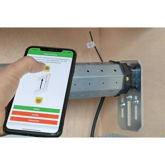 Schellenberg Funk-Rohrmotor Premium 6 MiniMax. Rollladenfläche: 4 m² bei Kunststoffrollläden, Einbaulänge: 570 mm, Zugkraft: 15 kg - Nahaufnahme eines Rolladenmotors, der mit einer Smartphone-App gesteuert wird, um die Rollladeneinstellungen zu konfigurieren.