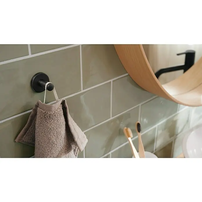 Tesa Moon Handtuchhaken - Graphit, Matt - Ein modernes Badezimmer mit grünen Fliesen, einem schwarzen Handtuchhaken mit Handtuch und Holzzahnbürsten.