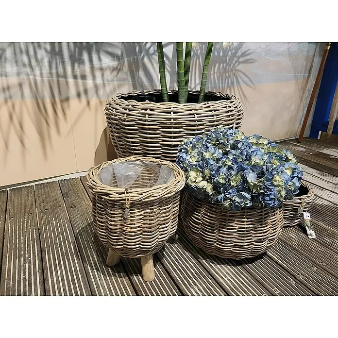 Van der Leeden Pflanzkorb - Ø x H: 41 x 54 cm, Rattan, Grau - Eine Nahaufnahme von drei geflochtenen Pflanzgefäßen unterschiedlicher Größe, eines mit blauen Hortensien und eines mit Grünpflanzen gefüllt.