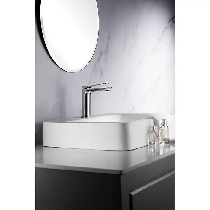 Imex Dinamarca Grifo de lavabo - Cromo - Elegante lavabo de baño con moderno grifo cromado y un elegante espejo redondo frente a una pared de mármol. Ideal para diseños de baño de lujo.
