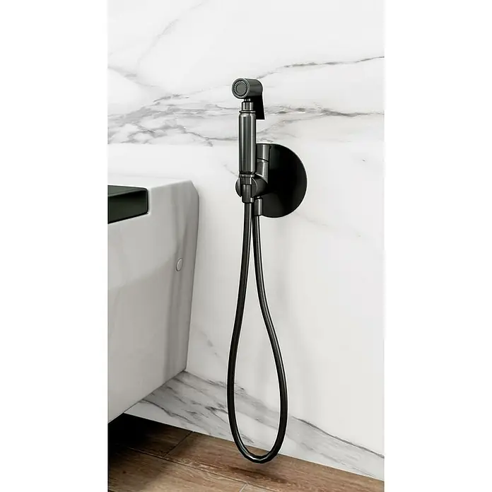 IO Round Ducha higiénica inodoro - Titanio - Primer plano de un rociador de bidé negro con manguera, montado en una pared de mármol, que muestra un detalle de baño elegante y funcional.