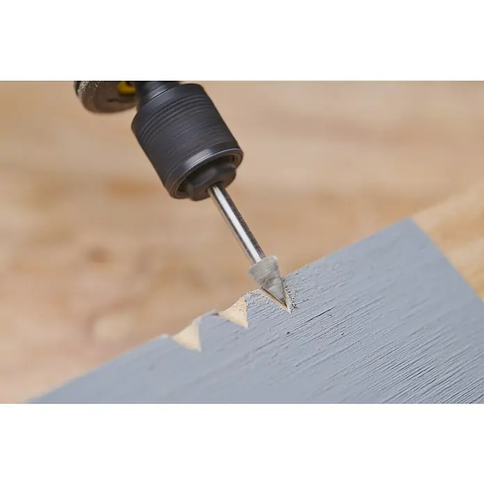 Ryobi Graviermesser RAR102 - Arbeitsdurchmesser: 6,35 mm, Passend für: Rotationswerkzeuge mit 3,2 mm (1/8") Spannzangenkapazität - Nahaufnahme eines Dremel-Werkzeugs mit Schleifaufsatz, das ein Muster in ein graues Holzstück fräst.