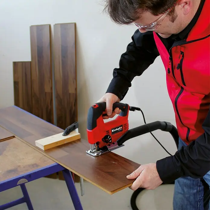 Einhell Elektro-Stichsäge TC-JS 80/1 - 1.000 /min - 3.000 /min, 80 mm - Ein Mann benutzt eine Einhell Stichsäge zum Zuschneiden von Laminat. Perfekt für präzise Schnitte beim Renovieren!
