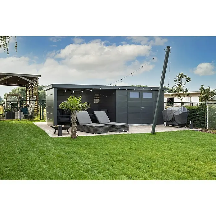 Telluria Metallgerätehaus Classico 3030 mit Lounge L links - Außenmaß inkl. Dachüberstand (B x T): 662 x 318 cm, Stahl, Anthrazit, Ohne Set - Graue Gartenlounge mit zwei Liegestühlen, Grill und einer kleinen Palme auf einer gepflasterten Terrasse mit Rasenfläche im Außenbereich.
