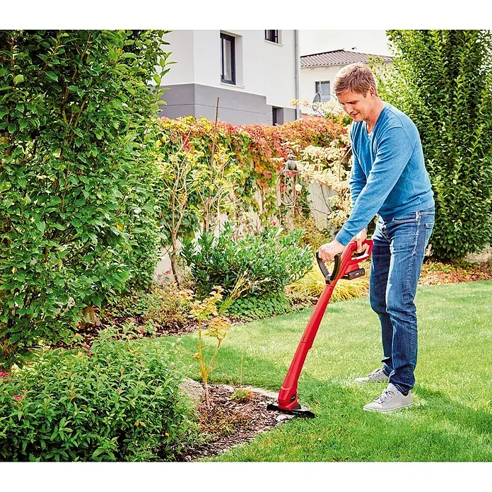 Einhell Power X-Change 18V Akku-Rasentrimmer GC-CT 18/24 Li P-Solo - 18 V, Ohne Akku - Ein Mann benutzt eine rote Einhell Akku-Rasenkantenschere, um die Rasenkante entlang eines Blumenbeets zu trimmen.
