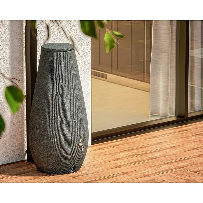 Arves Regenspeicher Drop - 200 l, Granitkörnung, 1 Stk. - Eine stilvolle graue Regentonne mit einem Hahn, die auf einer hölzernen Terrasse vor einer Wand steht, ideal für die Gartenbewässerung.