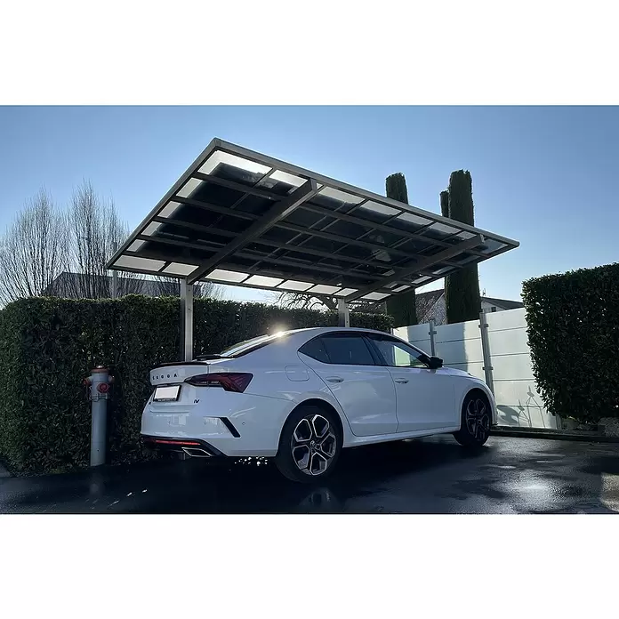 Ximax Solar-Set - 0% MwSt. gem. § 12 Abs. 3 UStG - 2.520 W, Passend für: Ximax Aluminium Design Carport Linea Sonderlänge 5558 x 2726 mm - Metall-Carport mit lichtdurchlässigem Dach schützt ein weißes Auto.