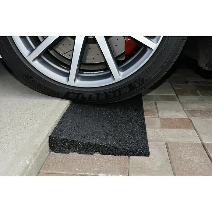 Gum-tech Auffahrrampe - Schwarz, 100 x 25 x 4,5 cm - Nahaufnahme eines Reifens, der über eine Rampe aus recyceltem Gummi auf ein höheres Niveau fährt, ideal für Garagenzugänge.