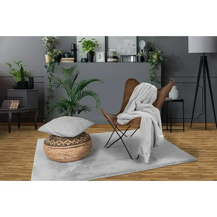Decke Happy - Silber, 200 x 150 cm, 100 % Polyester - Ein stilvolles Wohnzimmer mit einem weichen, grauen Teppich, einem Ledersessel und dekorativen Pflanzen.