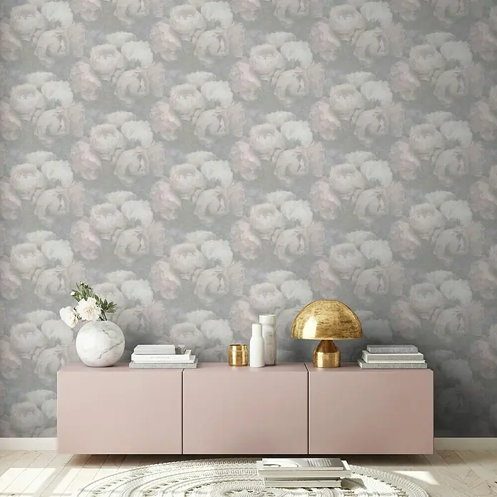 A.S. Création New Walls Vliestapete Rose - Weiß/Rosé, Floral, 10,05 x 0,53 m - Einrichtungsidee mit rosa Schrank, goldener Lampe, Büchern, Dekoration und Blumenvase vor einer Wand mit floralem Muster.