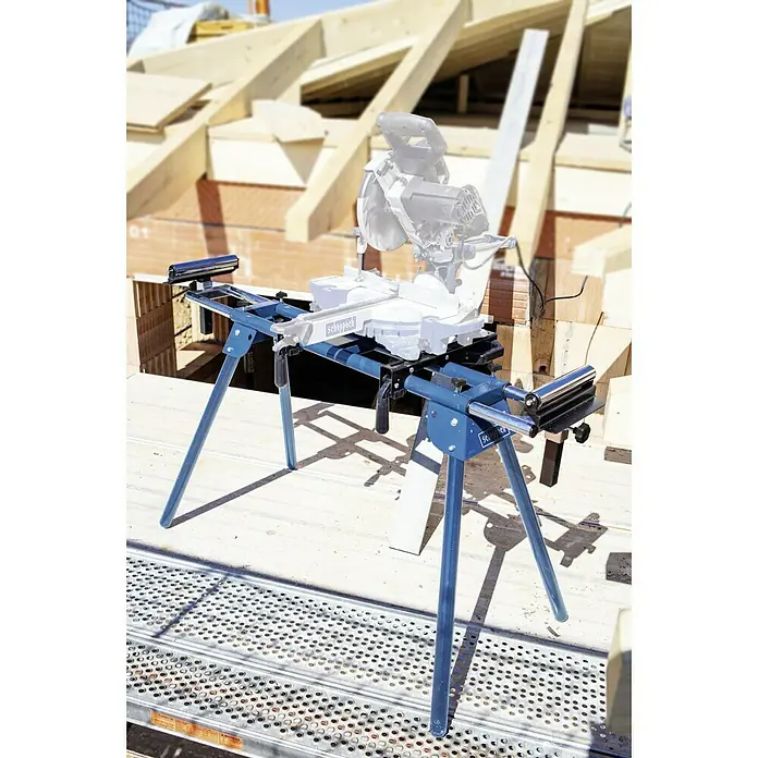 Scheppach Sägetisch UMF1600 - Geeignet für: Kappsägen, L x H: 1.000 x 810 mm - Das Bild zeigt einen blauen Scheppach Untergestell, der für eine Kappsäge verwendet wird, auf einer Baustelle. Das Untergestell ist stabil und einsatzbereit.
