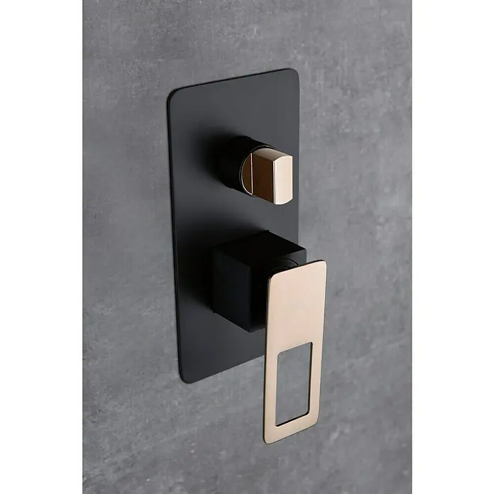 Imex Suecia Sistema de ducha empotrado - Con grifo monomando, Negro/Oro rosa - Primer plano de un elegante mezclador de ducha negro y dorado sobre una pared gris. Un detalle lujoso para cualquier baño.