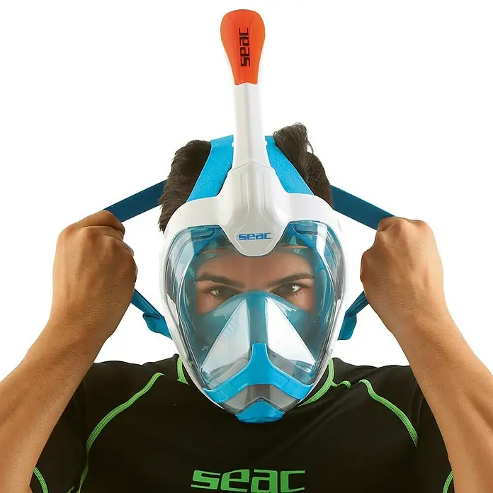 Seac Sub Máscara de Snorkel Mágica - L/XL, Plástico, Azul/Blanco - Un hombre se pone una máscara de esnórquel facial completa SEAC azul y blanca que tiene un tubo naranja.
