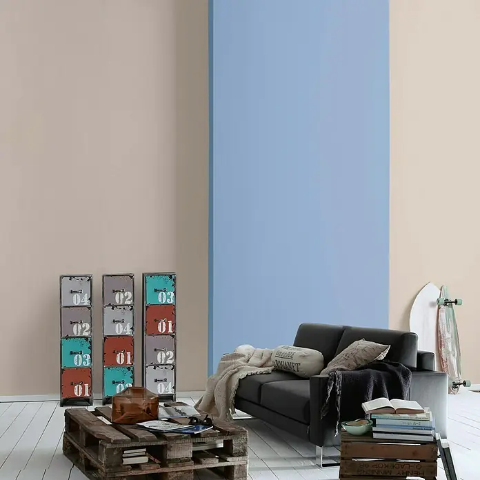 A.S. Création Vliestapete Glatte Wand Meistervlies 5 - Cappuccino, Uni, 10,05 x 0,53 m - Ein Wohnzimmer mit einem schwarzen Sofa, einem Couchtisch aus Paletten und Metallschränken.