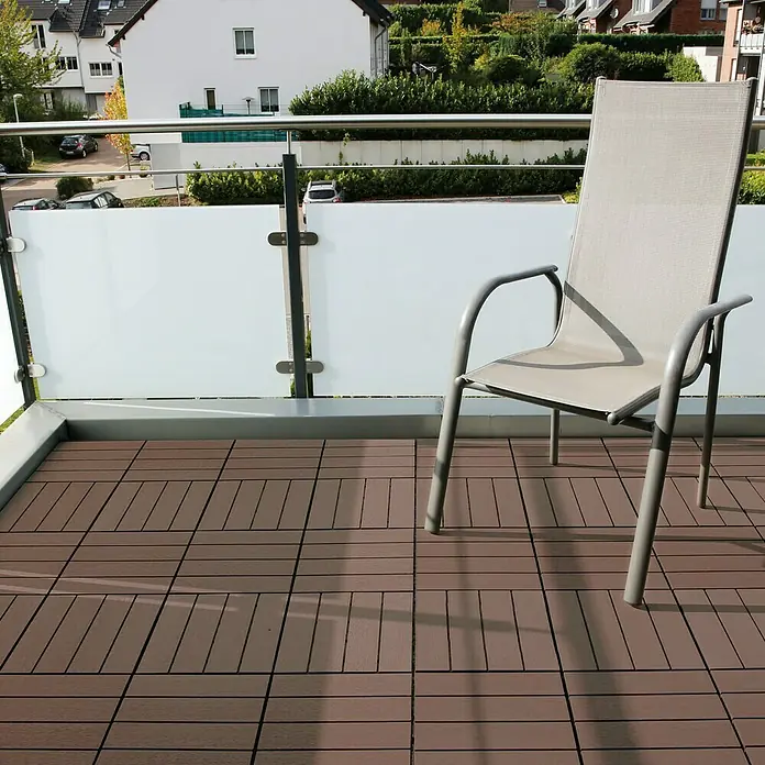 Klickfliese - WPC, 30 x 30 x 2,5 cm, 10 Stk., Marone - Ein grauer Stuhl steht auf einem Balkon mit braunen Fliesen und einer modernen Glasbrüstung. Der Stuhl lädt zum Entspannen im Freien ein.