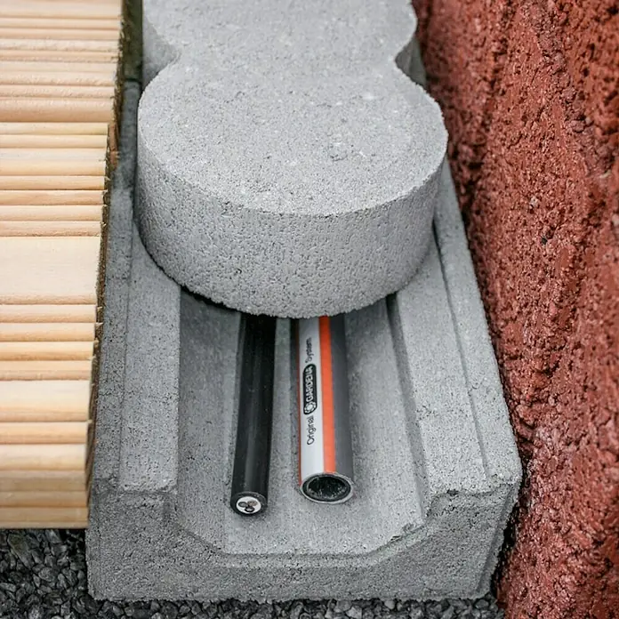 Christoph Kabelkanalstein - 20 x 12,2 x 5,9 cm, Beton - Nahaufnahme von einem Betonelement mit zwei Rohren, eines davon mit der Aufschrift "Original GARDENA System".