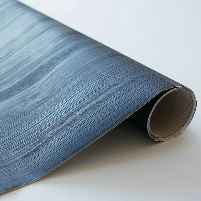 D-c-fix Lámina efecto madera Quadro - 150 x 67,5 cm, Azul noche, Autoadhesivo - Primer plano de un rollo de vinilo azul oscuro con grano de madera sobre un fondo blanco.