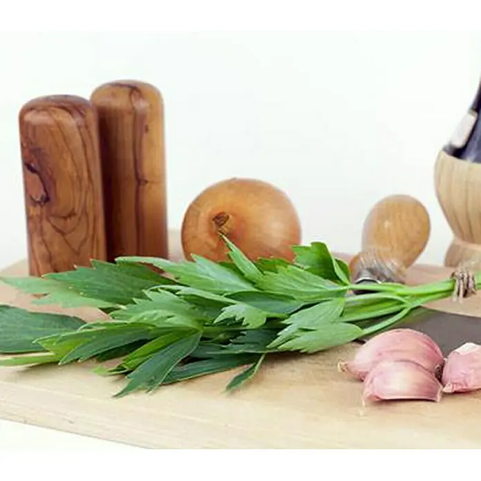 Piardino Apio de monte - Levisticum officinale - Hierbas frescas, ajo y cebollas en una tabla de madera, listas para cocinar una deliciosa comida.