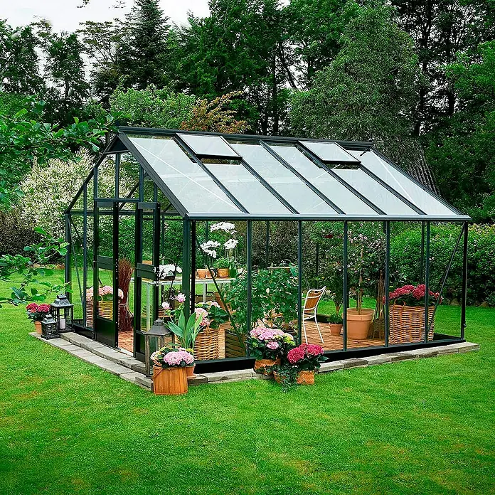 Juliana Gewächshaus Gärtner - Außenmaß inkl. Dachüberstand (B x T): 368 x 439 cm, Material Seitenwand: Glas, 3 mm, Anthrazit/Schwarz, Sicherheitsglas - Glashaus mit geöffneten Fenstern im Garten, umgeben von Blumen und Grünpflanzen. Der Fokus liegt auf dem Gewächshausdesign und der Gartengestaltung.
