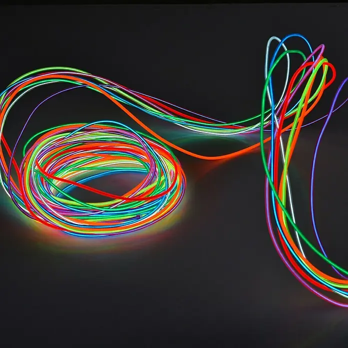 Tween Light Tira de luces LED - Largo: 3 m, 0,6 W, Naranja - Cables EL coloridos sobre un fondo oscuro que crean un ambiente moderno y vibrante. Ideal para decoraciones.