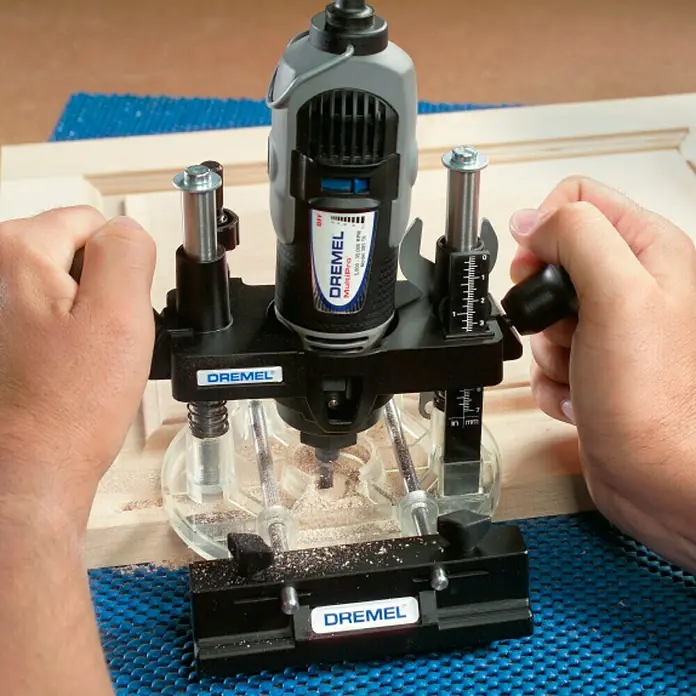 Dremel Oberfräsenvorsatz 335 - Oberfräsenvorsatz, Kantenführung, Kreisführung, Schablonenführung, Schlüssel - Das Bild zeigt einen Dremel MultiPro Frästisch in Aktion, der präzise Holzarbeiten ermöglicht. Ideal für Hobbybastler und Profis.