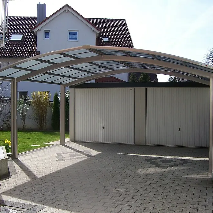 Ximax Carport Portoforte M 80 - Außenmaß inkl. Dachüberstand (B x T): 5,42 x 4,95 m, Doppelcarport, Edelstahloptik, Schneelast: 100 kg/m² - Ein Carport mit Glasdach und Metallrahmen, der Schatten spendet und Fahrzeuge vor Witterungseinflüssen schützt. Der Carport steht vor einer Garage.