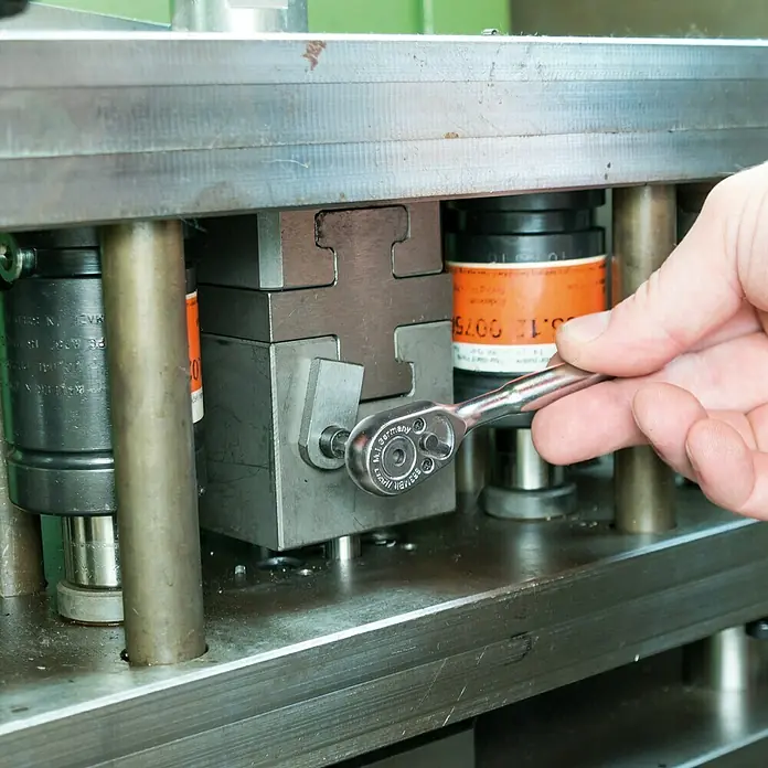 Hazet Umschaltknarre 863 MBIT - Antriebsgröße: ¼″ Sechskant, 89 mm - Nahaufnahme eines Mannes, der mit einer kleinen, verchromten Knarre an einer Maschine arbeitet. Das Werkzeug liegt gut in der Hand.