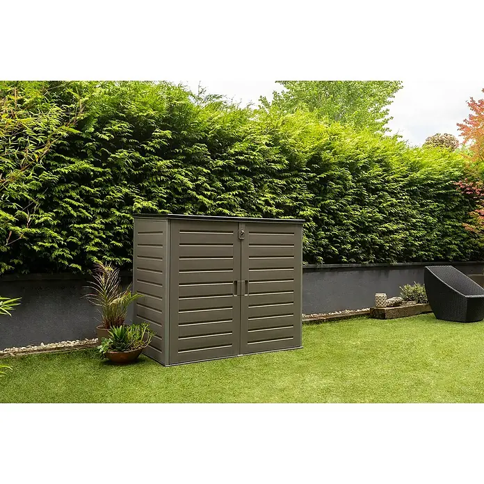 Truhe The Space Plus - L x B x H: 140 x 82 x 124 cm, Anthrazit/Schwarz - Geräumiger Gartenschrank in Grau mit horizontaler Struktur vor grüner Hecke und Rasen. Ideal für die Aufbewahrung von Gartengeräten.