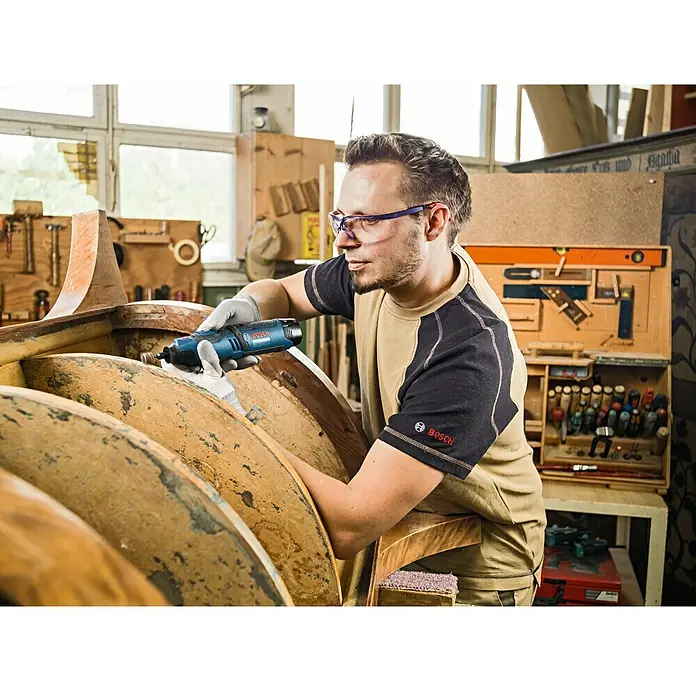Bosch Professional Akku-Multifunktionswerkzeug GRO 12V-35 - 12 V, Leerlaufdrehzahl: 5.000 U/min - 35.000 U/min - Mann, der mit einem Bosch-Elektrowerkzeug an einem Holzboot arbeitet.