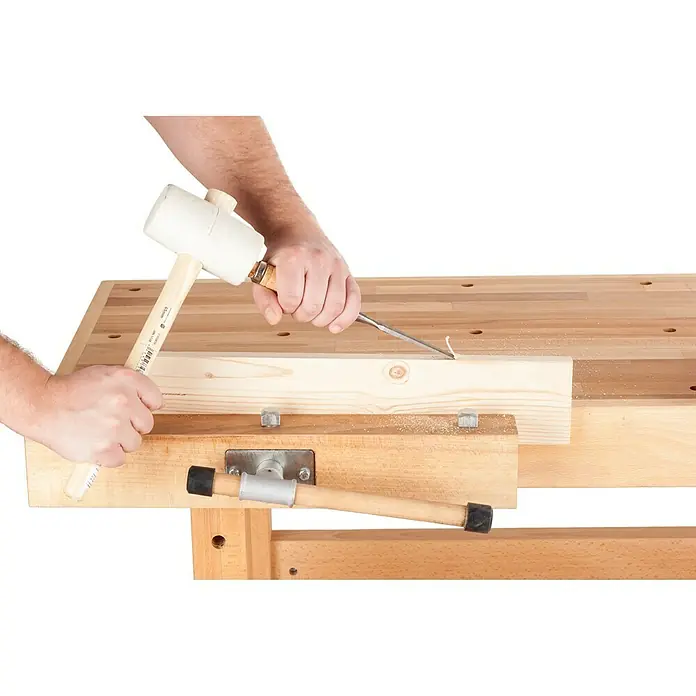 Banco de trabajo - L x An: 1.400 x 500 mm, Altura de trabajo: 830 mm, Carga soportada: 400 kg, Marrón - Un carpintero usando un cincel con un mazo de goma en un banco de trabajo para dar forma a la madera. Herramientas de precisión ideales para proyectos de carpintería.
