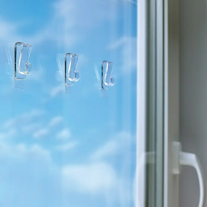 Tesa Klebehaken - Geeignet für: Glas, Belastbarkeit: 1 kg, 2 Stk., Transparent - Klare Klebehaken auf einem Fenster mit Blick auf einen blauen Himmel, ideal zum Aufhängen von Dekorationen oder kleinen Gegenständen.