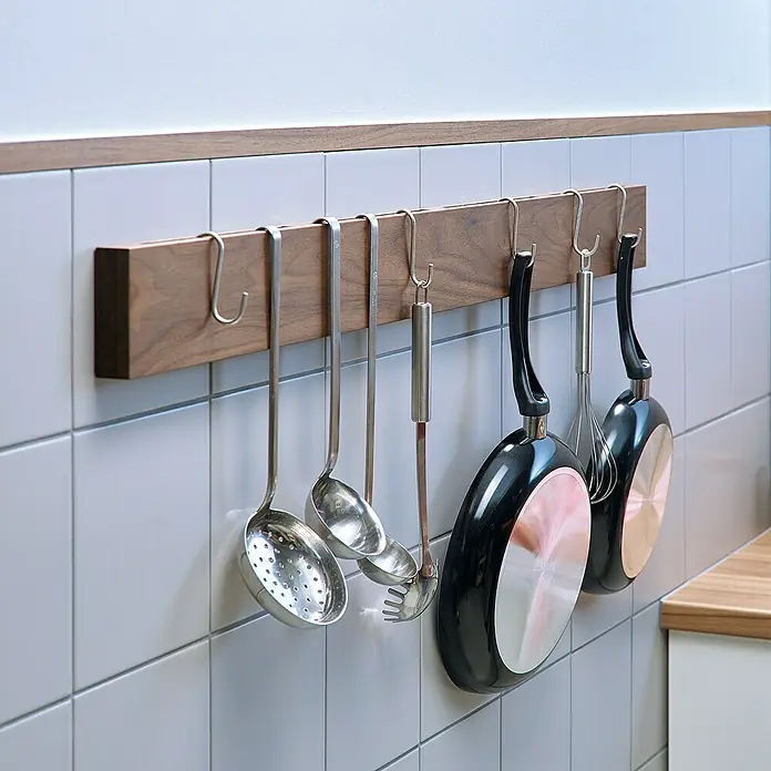 Tesa Montageband - Geeignet für: Fliesen, Belastbarkeit pro m: 100 kg, 1,5 m x 19 mm - Küchenutensilien wie Pfannen und Schöpfkellen hängen an einer hölzernen Küchenleiste an einer gefliesten Wand. Praktische Küchenaufbewahrung.