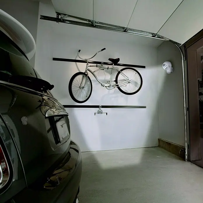 Ledvance Sensor de movimiento Spylux - Diámetro: 68 mm - Bicicleta crucero plateada colgada elegantemente en la pared de un garaje, un ejemplo de almacenamiento elegante y utilización del espacio.