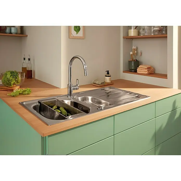Grohe Start Loop Spültischarmatur - Chrom, Glänzend, Höhe: 357 mm - Eine Edelstahlspüle mit Abtropffläche und einer Spülmittelablage, die mit Gurken gefüllt ist, steht auf einer grünen Küchentheke.