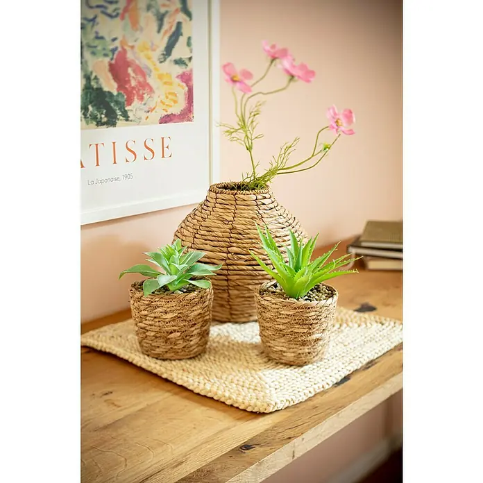 Tisch-Set - 38 x 38 cm, Natur - Nahaufnahme eines Dekoration-Arrangements mit zwei kleinen Sukkulenten in Körben und einer Vase mit rosa Blumen auf einem Tisch.