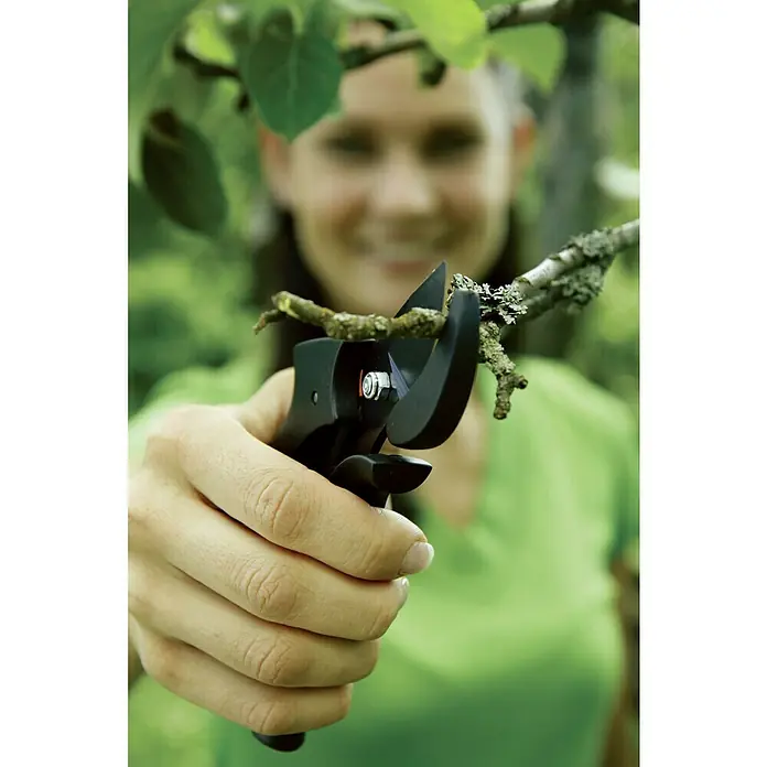 Fiskars Gartenschere Pro P90 - Bypass, Max. Aststärke: 26 mm - Eine Frau benutzt eine Astschere, um einen kleinen Ast abzuschneiden. Die Astschere ist schwarz und hat eine silberne Schraube.