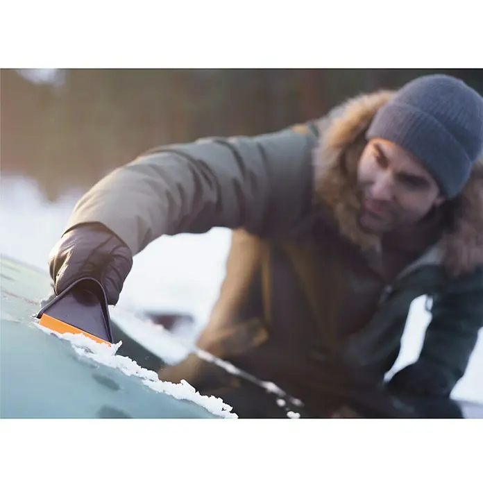 Fiskars Eiskratzer Solid - Breite Schaberkante: 9,5 cm - Mann kratzt mit einem orangefarbenen Eiskratzer Eis von einer Windschutzscheibe.